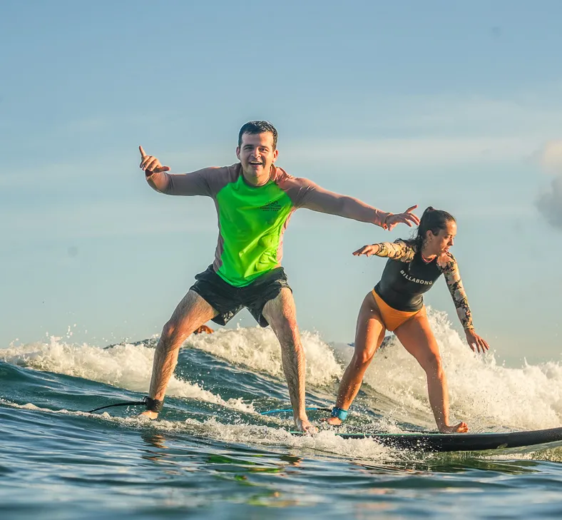 Surf instructor helping a beginner surf at Padang Padang